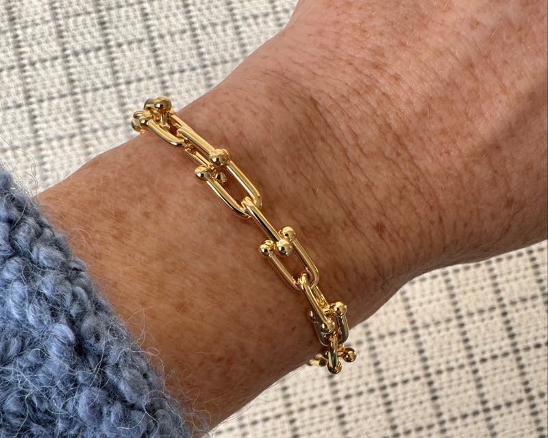 Gold bracelet on a wrist with a textured background
